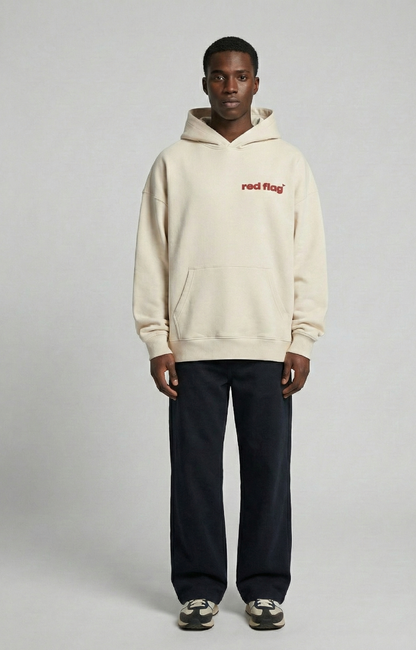 Person wearing a beige hoodie with 'red flag' text on a gray background